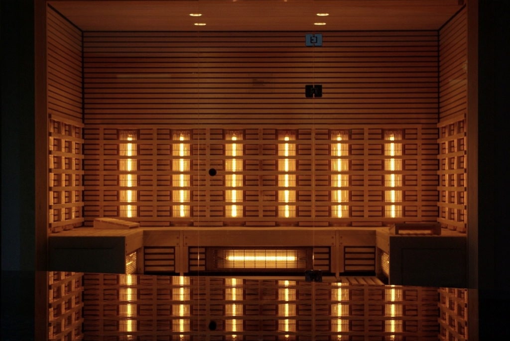 Infrared cabin with full-spectrum emitter panels behind the bench