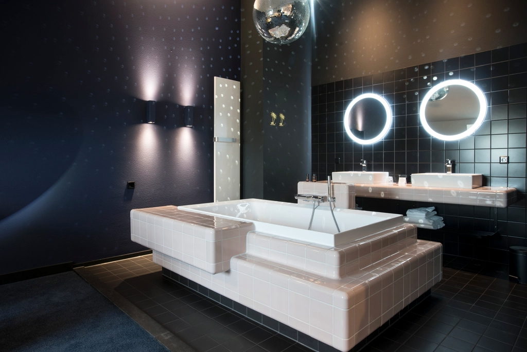 Dark tiled wet room with twin stone basins and low wall lighting